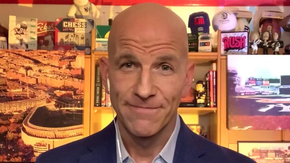 A close up photo of Jared Max, smiling towards the camera and taken in his home studio.