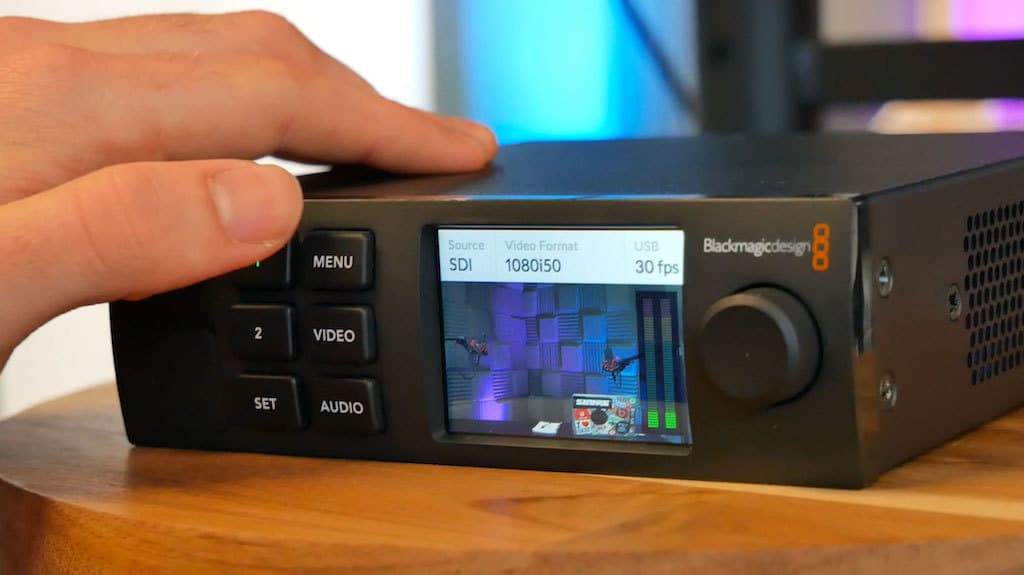 Image shows a hand pressing a button on the Blackmagic Web Presenter.