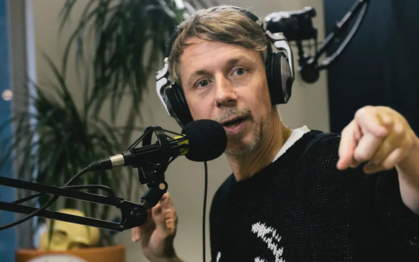 Image shows the broadcaster and DJ, Gilles Peterson, presenting a radio show and pointing to something out of shot.