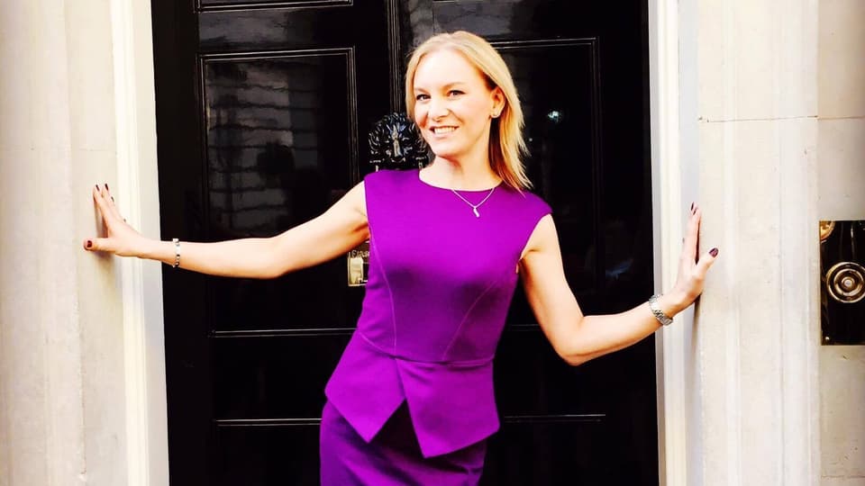 A photo of Stephanie Hirst, smiling in front of the door for Number 10 Downing Street.