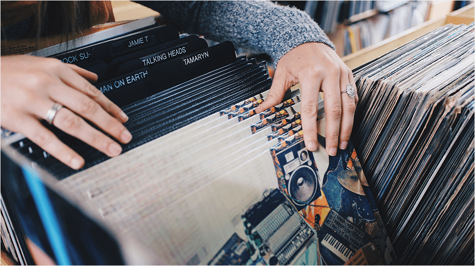 Image shows a pair of hands searching through a selection of vinyl records.