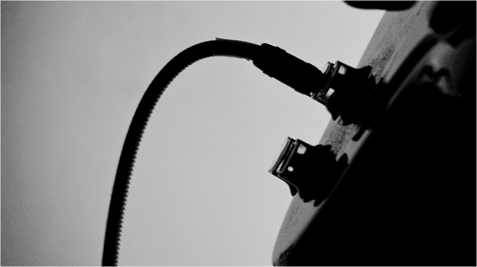 This is a black and white image of a wire and small input into a mixing desk but a very zoomed image, so that all is visible really is the wire.