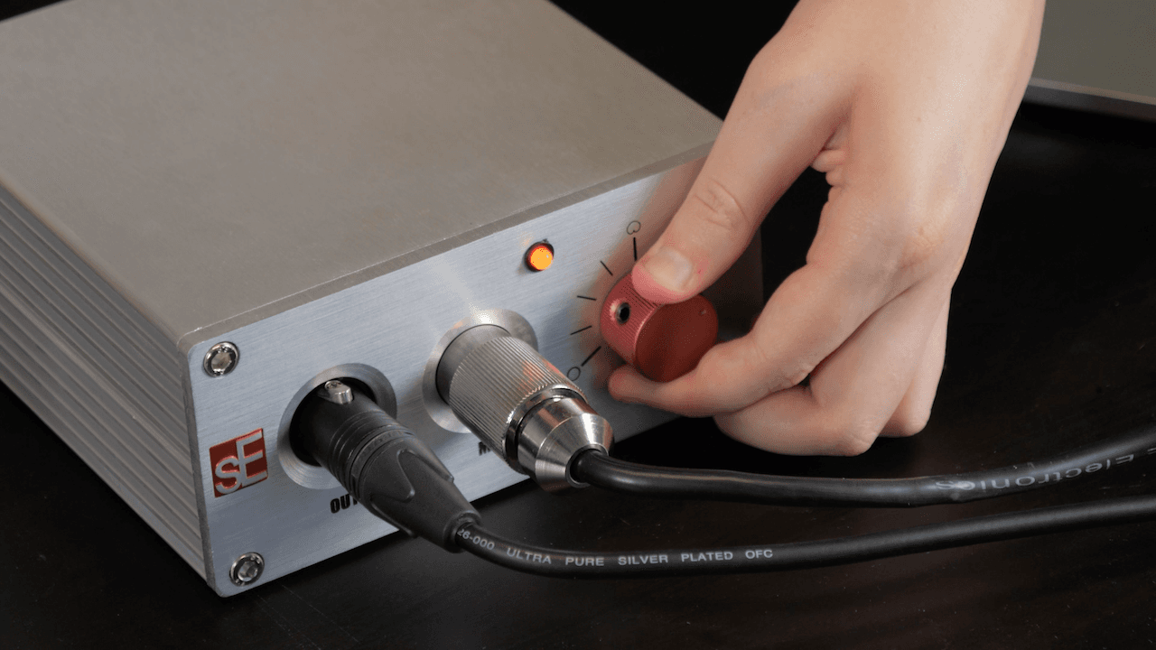 Image shows someone adjusting a dial on the sE Electronics Z56000A II power supply box.